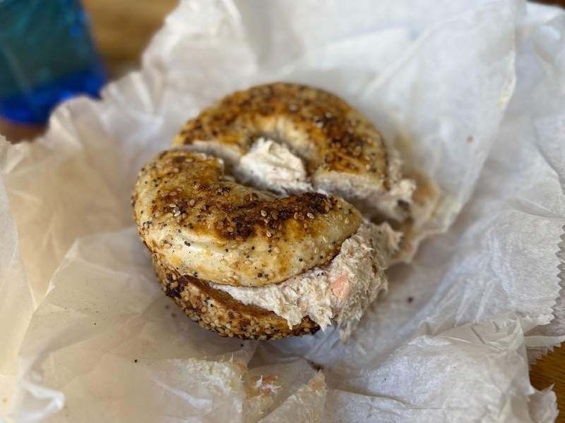 Gluten free bagel with salmon salad sitting on parchment paper.