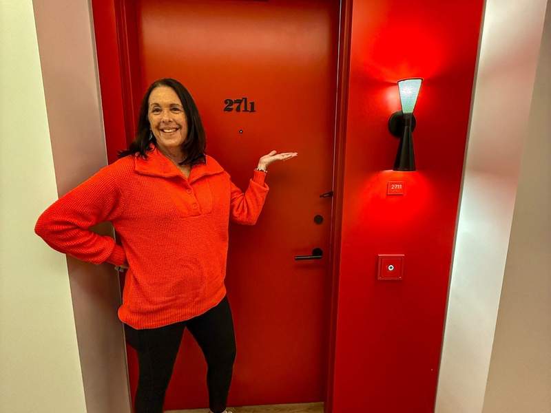 Woman posing in front of red hotel door
