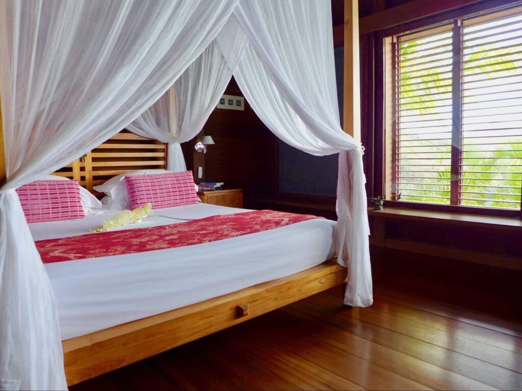 king size bed draped with mosquito netting in caribbean beach house