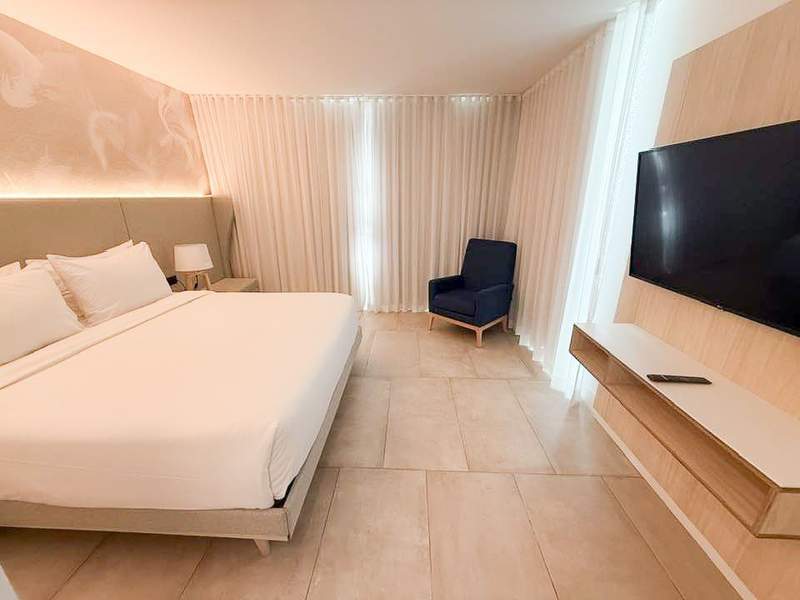 King bedroom in a resort hotel suite with pink walls and white bedding.