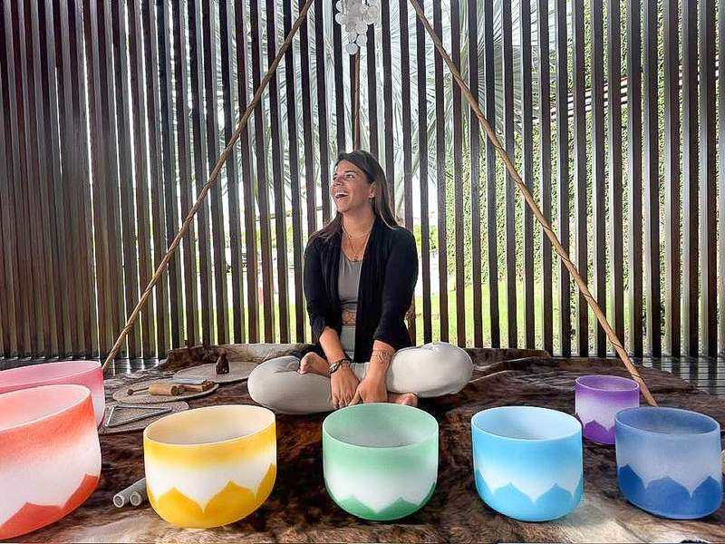 Woman sitting near colorful sound bowls during wellness class.