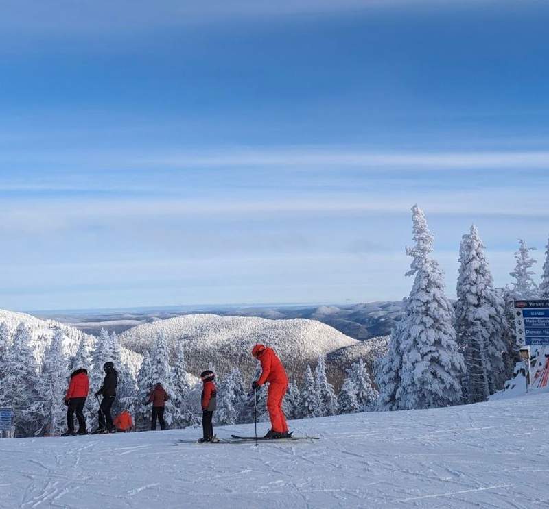 Families getting ready to ski down the slopes in a winter wonderland at Mont Tremblant.