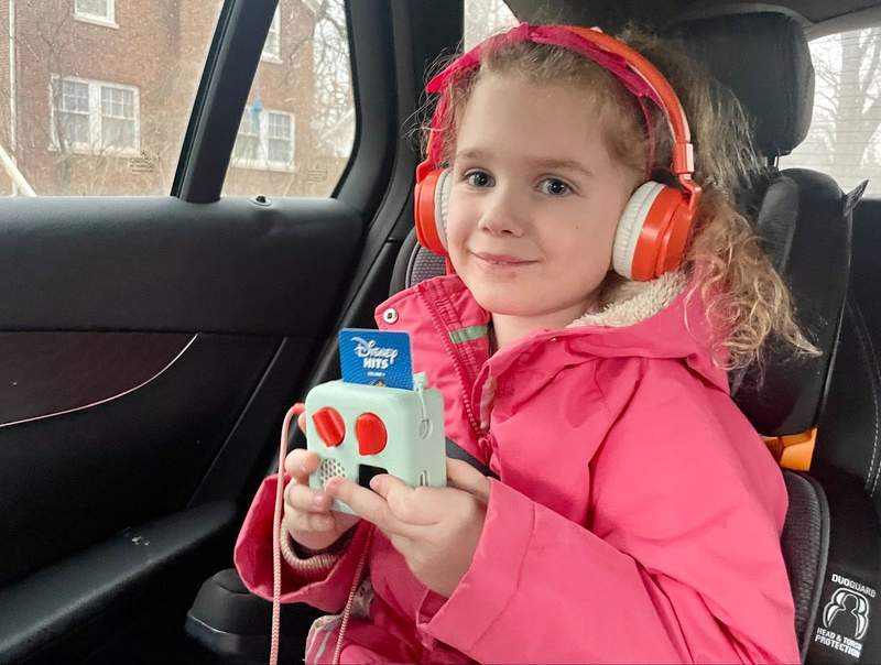 Girl listens to music on a portable device while riding in a car.