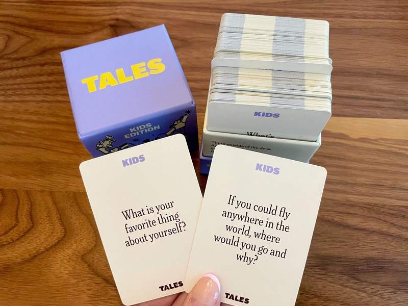 A hand holds two conversation cards from a deck.