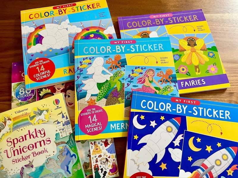 An assortment of color by sticker books are displayed on a table.