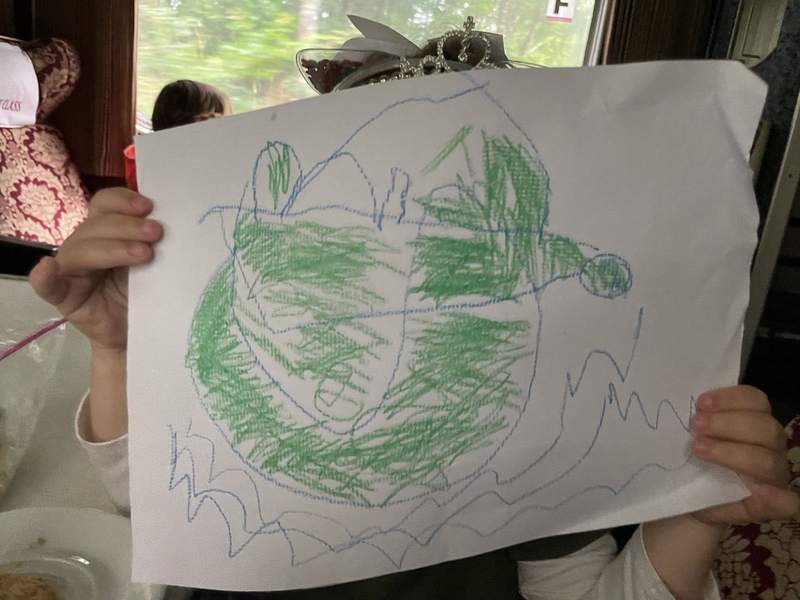 A young girls holds up her drawing made with crayons.