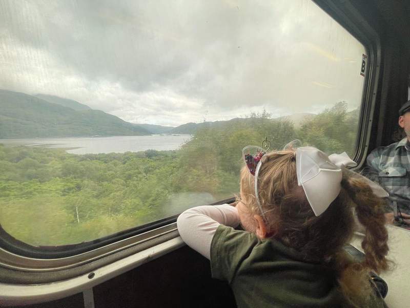 A young girl looks out a train window.