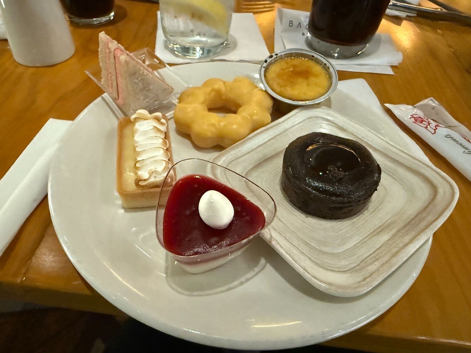 plate filled with donuts, creme brulee, tarts, and a cake