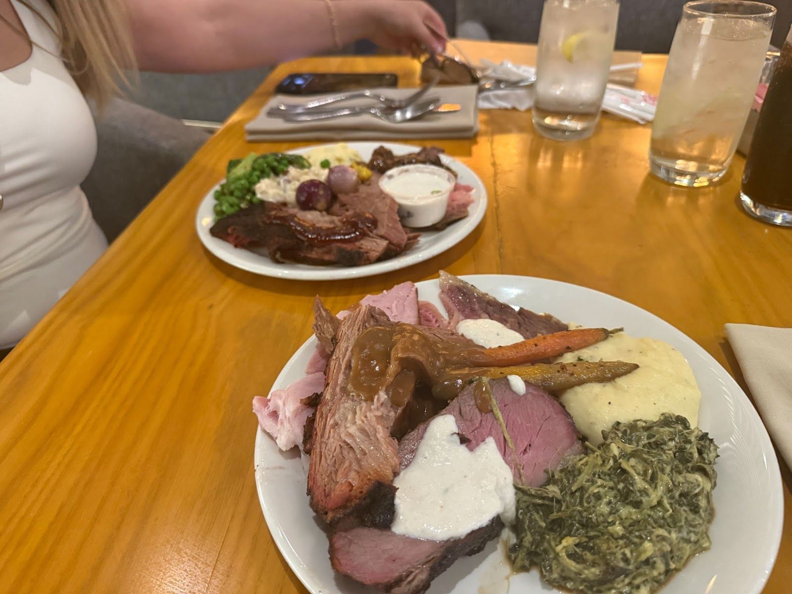 two plates of food fulled with steak, potatoes, sauce, and creamed spinach