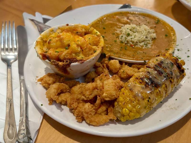 A dinner plate with fried crawfish tails, crawfish mac and cheese and crawfish étouffée with grilled corn on the cob. 