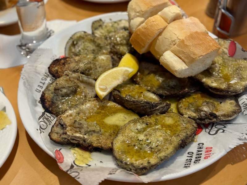 A plate of chargrilled oysters with bread and lemon wedges.