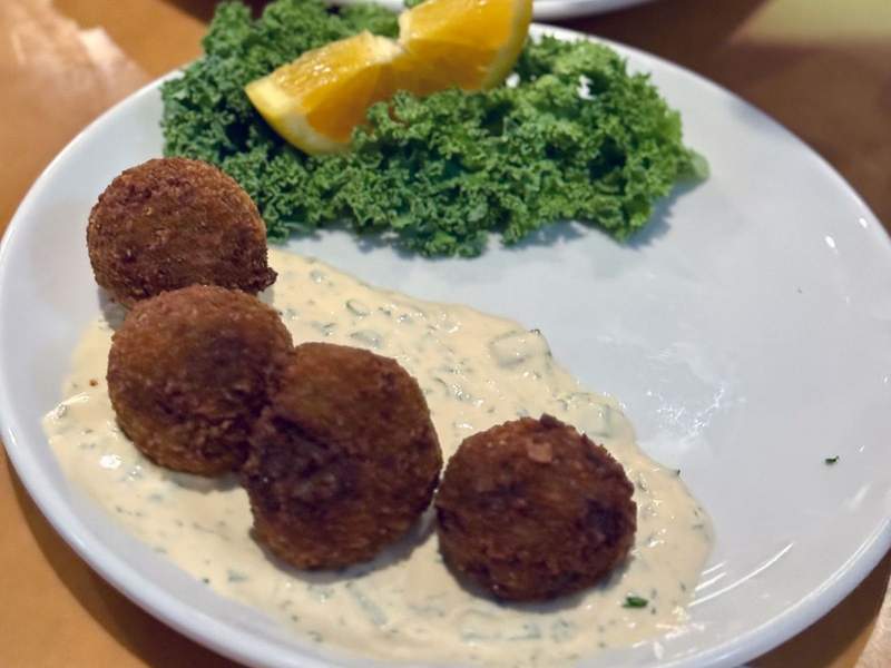 A plate with four Boudin Balls sitting in a creamy white sauce.