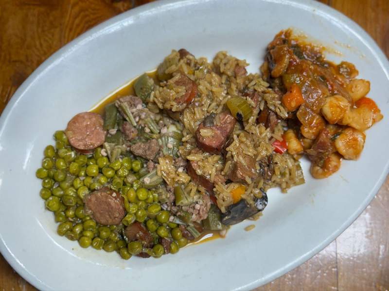 A dinner plate full of traditional Cajun foods, including gumbo, jambalaya, okra, andouille sausage and peas.