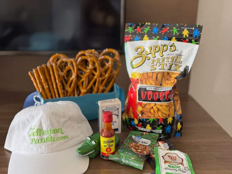 A table with pretzel stix, a baseball hat, hot sauce and several spice packets.