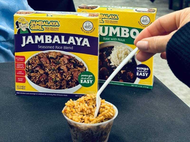 Two boxes of spice mixes from Jambalaya girl along with a small bowl of jambalaya and rice. 