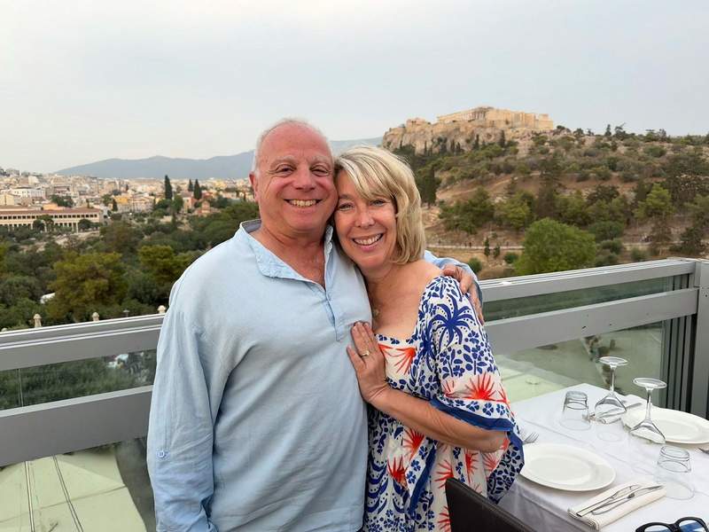 Couple posed at a restaurant  in front of Acropolis.