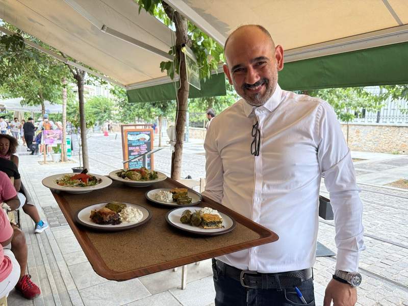 Smiling waiter delivering a tray of food.