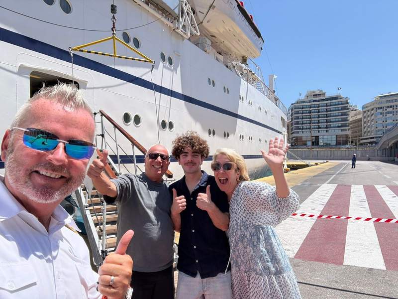 Family waiving as they're boarding a small cruise ship.