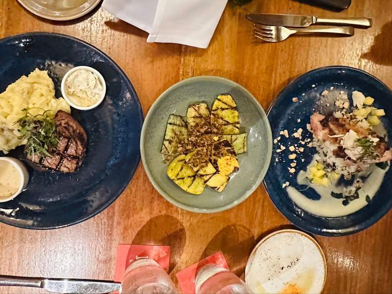 A table at a restaurant viewed from above with 2 meals and a salad.