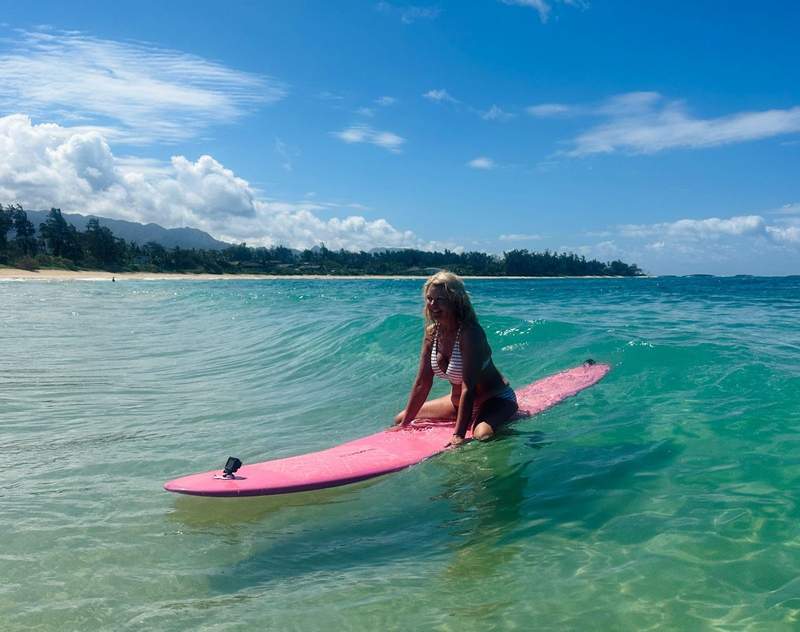 A woman on a pink surfboard in the ocean.