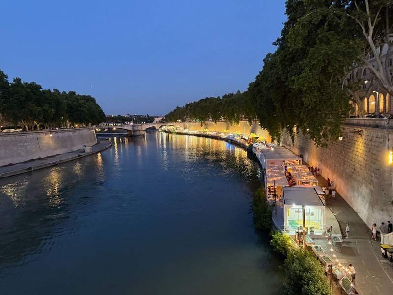 Streetlights illuminate the river walk along the Tiber River in Rome.
