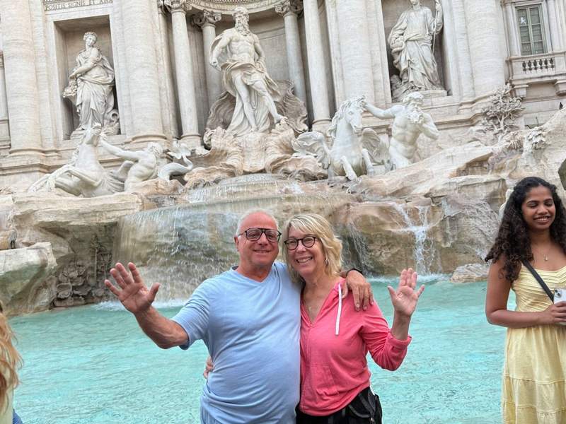 couple standing in front of Trevi Fountain early in the morning.