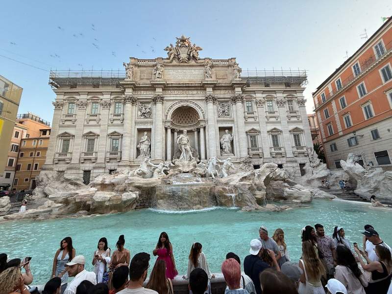 Trevi Fountain in Rome with a small crowd of people in front.
