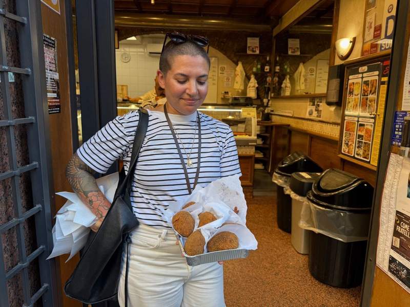 Woman standing with a basket of suppli in a Roman restaurant. 