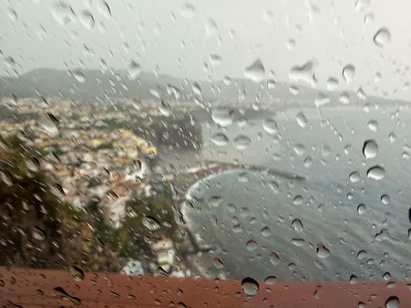 Looking out a rain-covered window down at a town on the Amalfi Coast