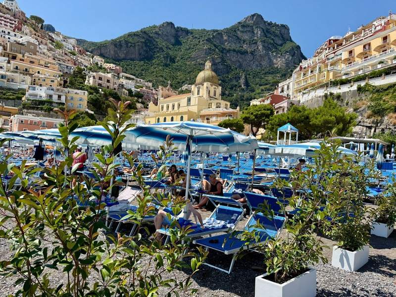 Beach chairs line up in front of the town, climbing the coastal hills.