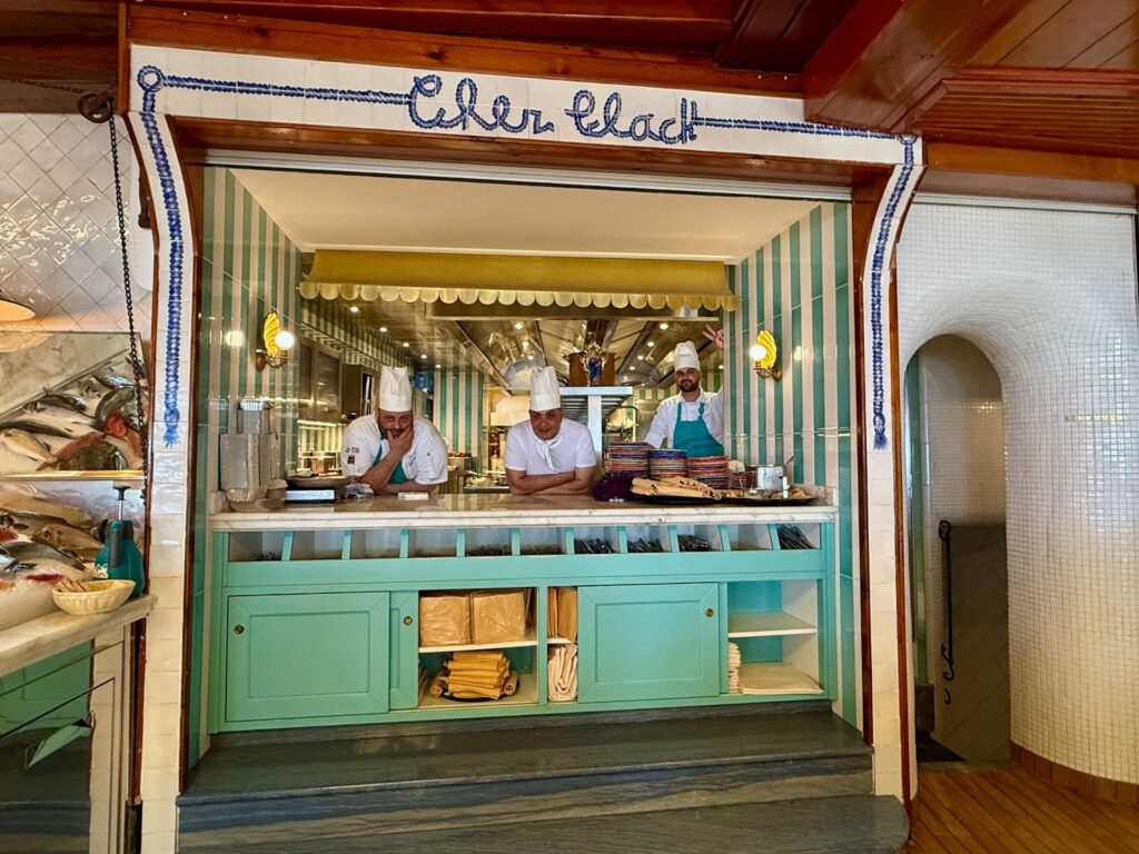3 chefs in various poses in the serving window of a restaurant in Positano