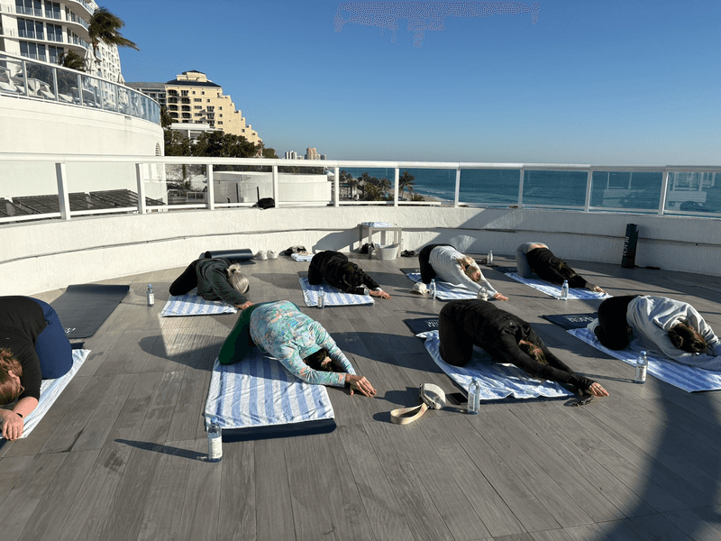 People stretching in a yoga class next to the ocean in Fort Lauderdale Beach, FL