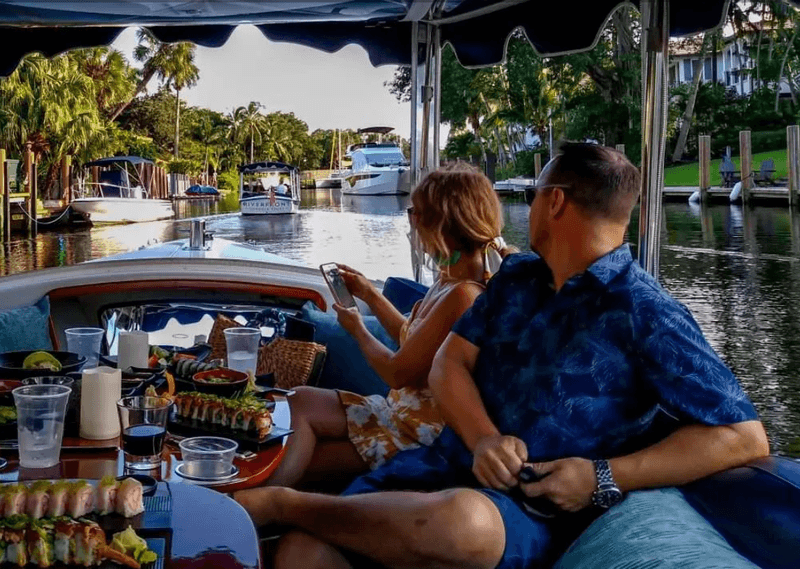A couple watching the boat view while sitting in a gondola ride with food in Fort Lauderdale Beach
