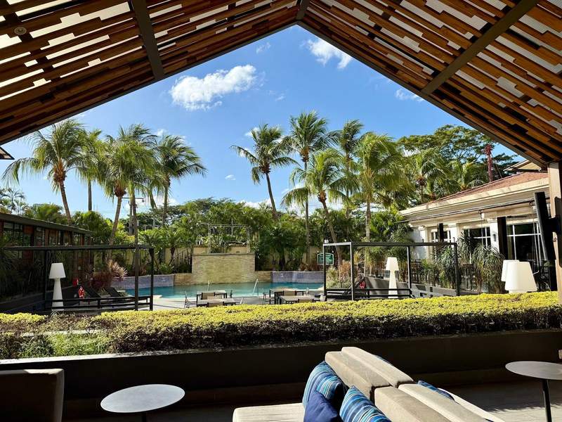 Poolside tables and chairs with a shaded sitting area in a luxury hotel. 