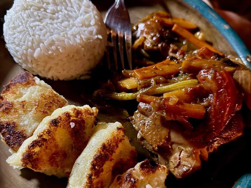 A plate of food with rice, vegetables, and potato patties.