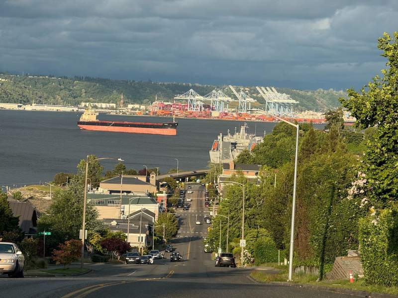 Road going down a hill to Old Town Tacoma with waterfront and ships waiting to go into the Port of Tacoma. 