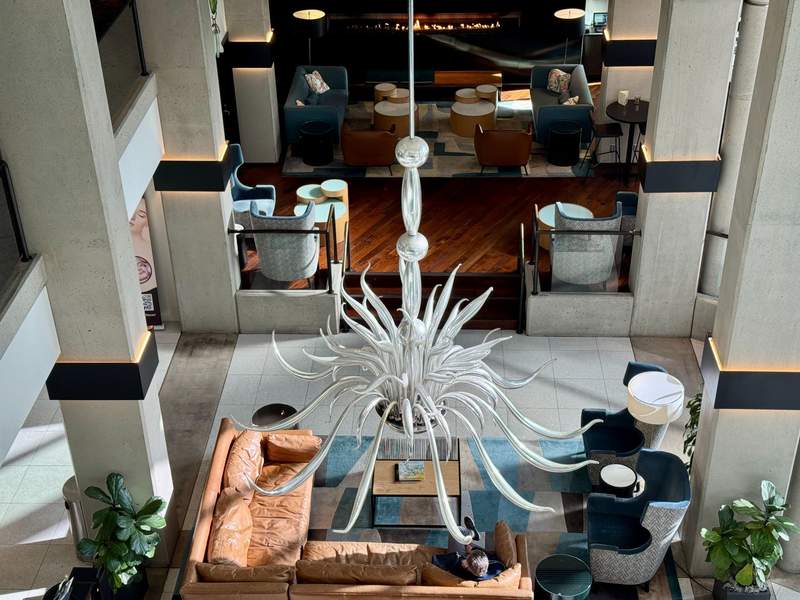 Hotel Lobby with seating and a large white blown and mirrored glass chandelier. Photo taken from above.