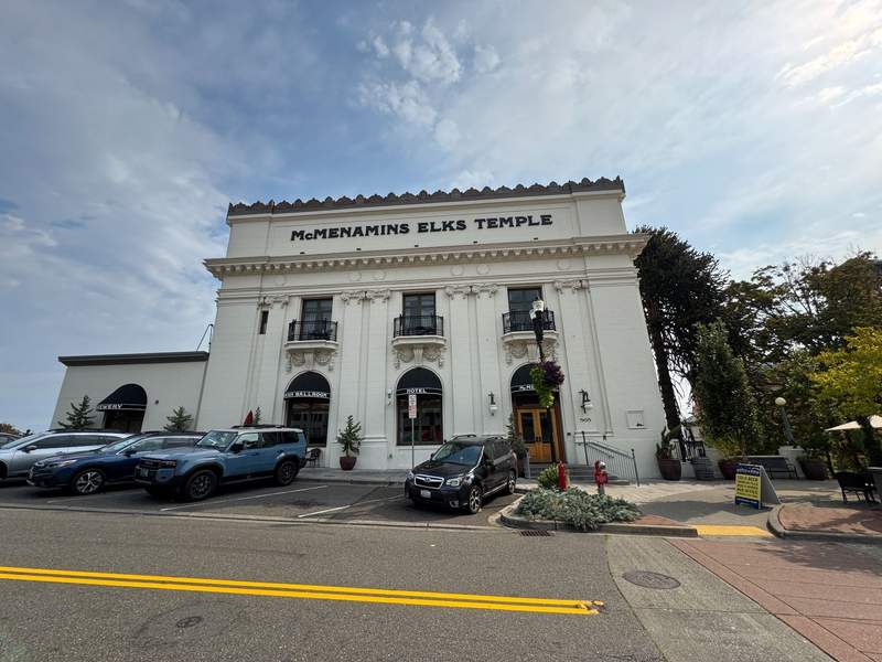 McMenamins Elks Temple Tacoma, a large white historic building with three upper windows with balconies, two lower arched windows and a large glass and wooden front door.