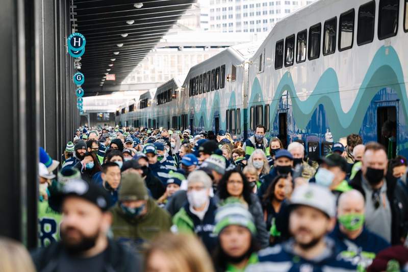 Train station with sports fans crowding the station as they head to a game.