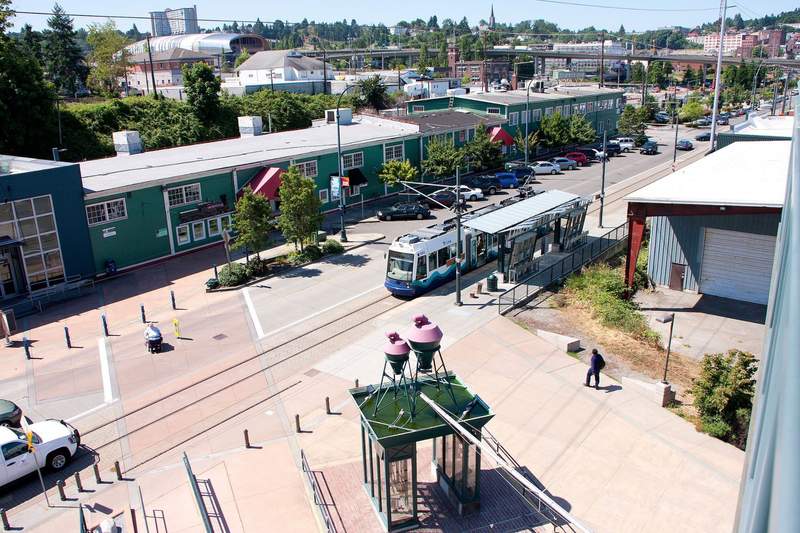 Tacoma Light Link Rail at the Tacoma Dome Station. Across the street is a long green historic building, Freighthouse Square.