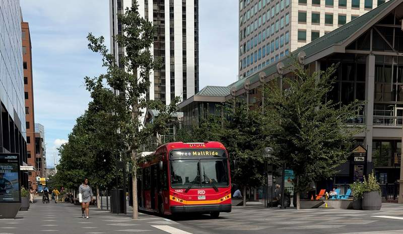 People walking on 16th Street on the left. A big red bus in the middle labeled “MallRide.” Buildings on the right.