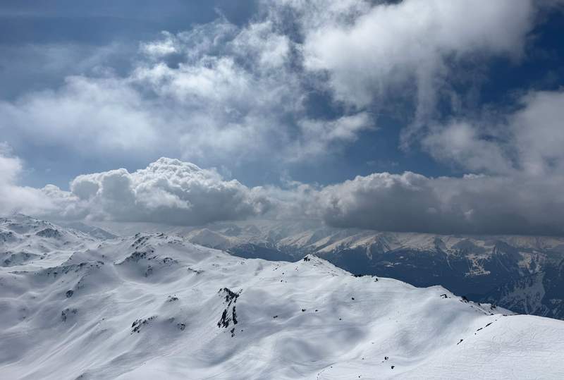 Panoramic view of snow-covered French Alps mountain peaks and dramatic clouds from Restaurant Le 2800 at Les Menuires in Les 3 Vallees.