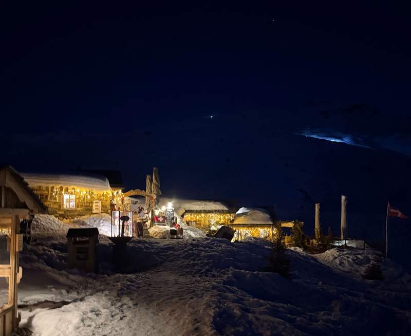Chez Pepe Nicolas mountain restaurant at night in Val Thorens Les 3 Vallees with warm glowing lights illuminating snow-covered alpine chalets under a dark winter sky.