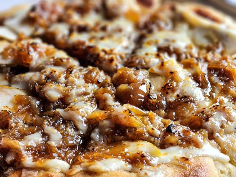 Closeup view of pizza with caramelized onions and cheese