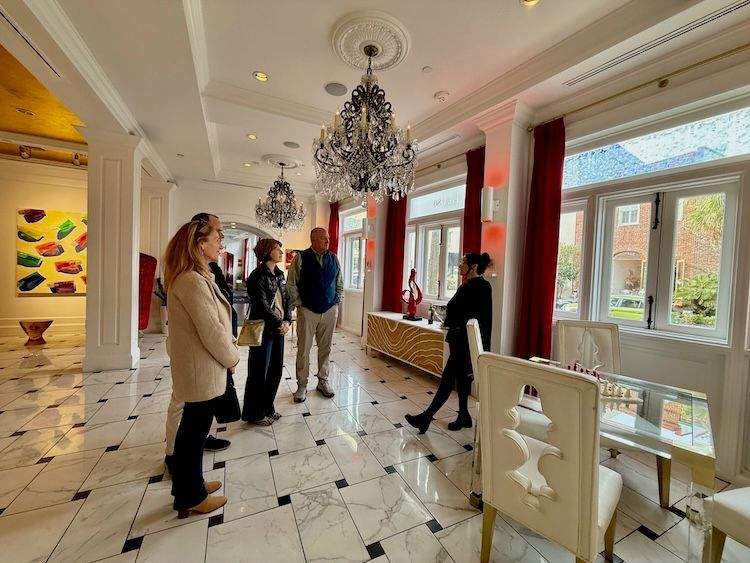 Guests stand in The Vendu’s colorful lobby listening to a curator speak