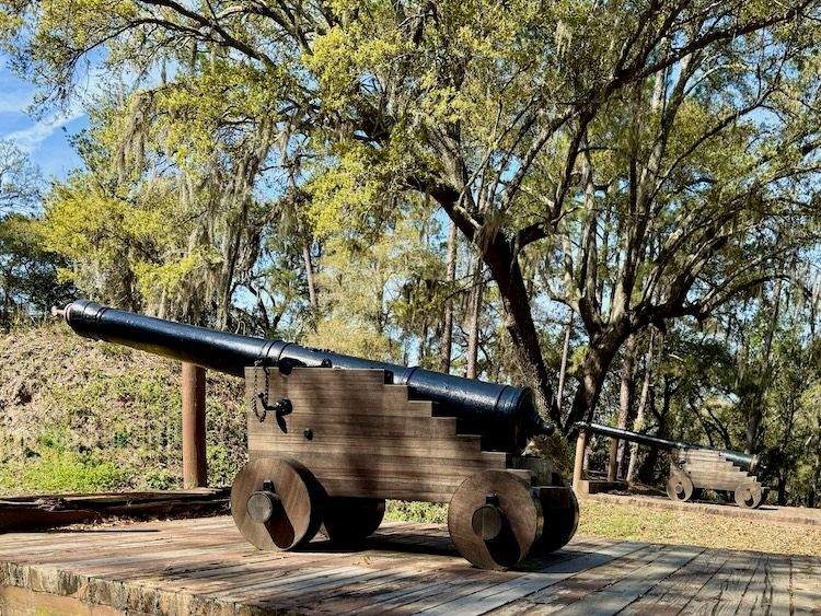 Cannons on a wood platform surrounded by trees at Charles Town Landing