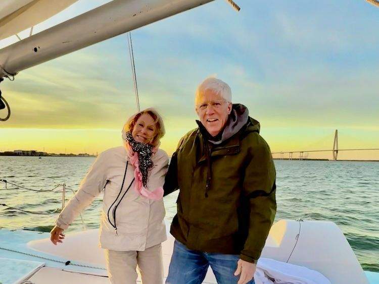 A couple sails in Charleston Harbor at sunset with the Arthur Ravenel Jr. Bridge visible in the background