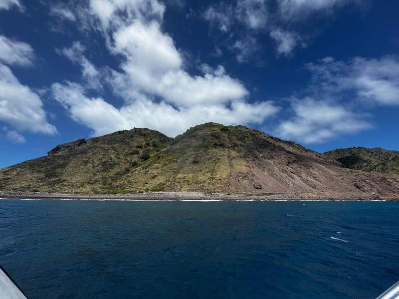 View of Saba from the water, showing the island rising steeply from the sea.