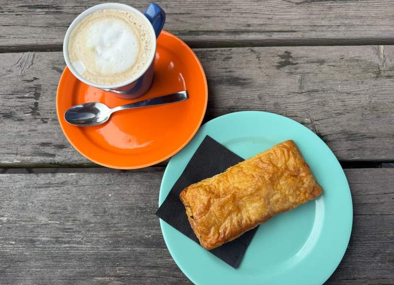 Coffee and pastries on a table at Bizzy B café, with a relaxed setting where locals gather and people pass by.