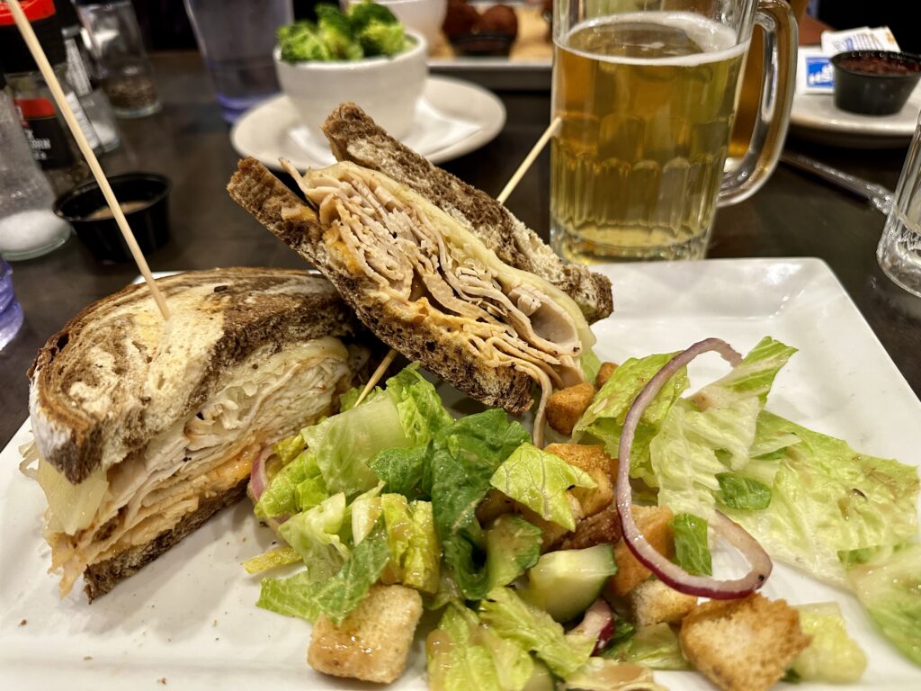 Smoked turkey Reuben at Bull & Bones Brewhaus & Grill in Christiansburg, VA with beer mug in background.